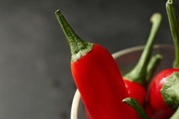 Glass of fresh chili peppers on dark background, closeup
