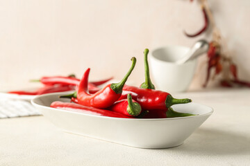 Plate of fresh chili peppers on light background