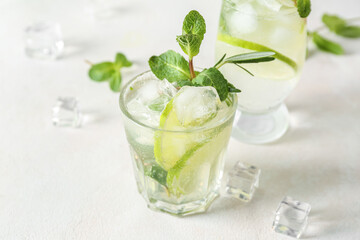 Glass of tasty mojito on light background