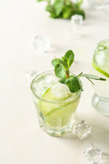 Glass of tasty mojito on light background