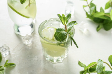Glass of tasty mojito on light background