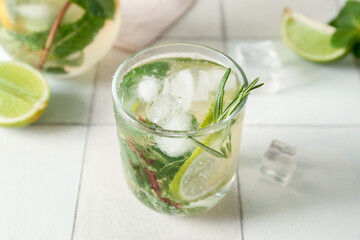 Glass of tasty mojito on light tile background