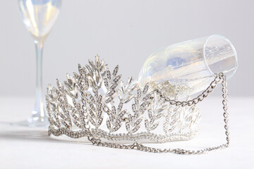 Beautiful tiara, glasses and necklace on white table, closeup. Prom concept