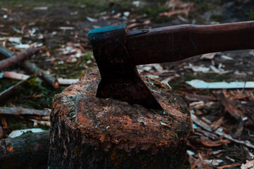 Axe tool is on the log. Harvesting firewood in the village with hatchet in the dark. Timber on the ground in the countryside. House of farmer and woodcutter. Power of sport vintage retro eco farm.