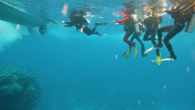 End of guided dive tour, group of divers arrive at speed boat, slow-motion
