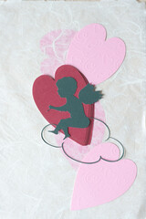 stylized cupid or putto or eros with wings and hearts on textured paper