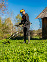 Gardener working on cutting lawn on countryside with barn in the background