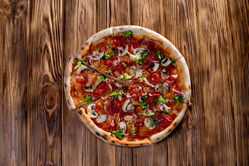 Vegan pizza with tomato sauce, cherry tomatoes, mushrooms, broccoli, red onion on woden background. View from above