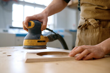Closeup craftsman hands working with eccentric grinding machine