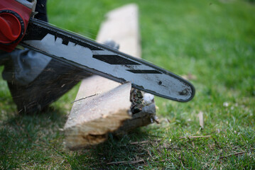 a man cuts a wooden plank with a chainsaw