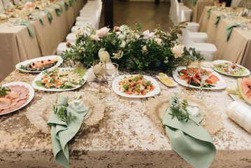 Festive table setting with olive napkins, golden plates and greenery branches