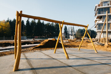 construction of a wooden playground with swings near the house in a residential area