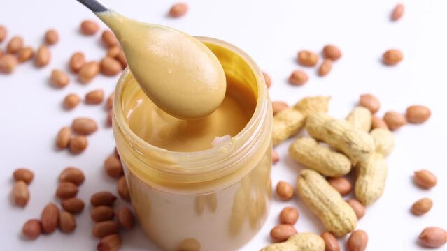 peanut butter and raw peanuts on a light background