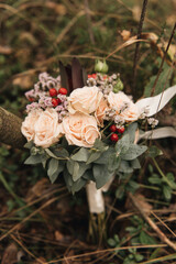 Beautiful wedding bouquet with protea and roses, wedding rings on a forest background