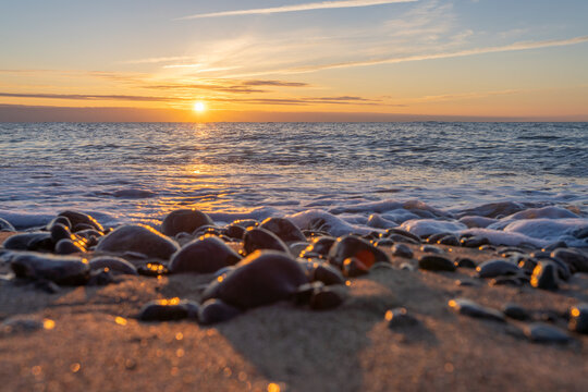 traumhafter, oranger, Sonnenuntergang zwischen Felsen im Meer der Ostsee bei Dranske auf Rügen	
