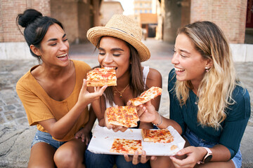 Funny group of three girls and they have fun eating pizza in the touristic city. Italian woman...