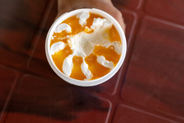 Mango and vanilla flavor cup Ice cream in wooden table holding by a kid
