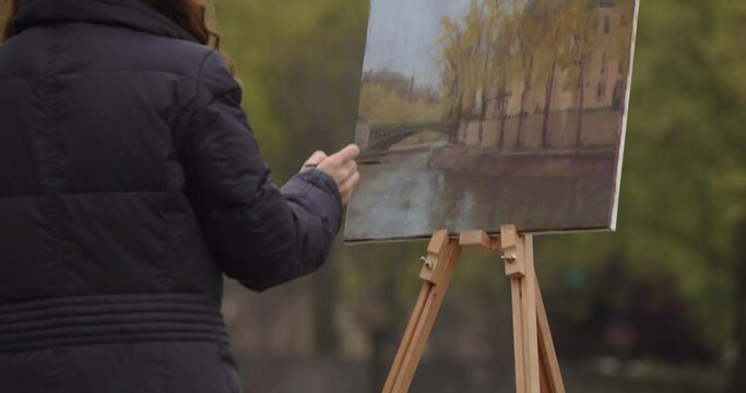 Female street art painter has some sketch practice with Paris city landscape. Experienced European woman artist draws new painting near the river. Painter and her lifestyle hobby leisure
