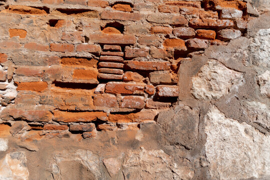Muro antiguo de ladrillos y cemento con revoque roto 