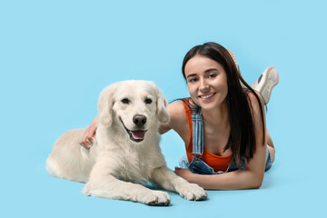 Happy woman with cute Labrador Retriever dog on light blue background. Adorable pet
