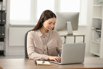 Hotline operator with headset working on laptop in office