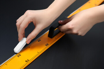 Woman drawing with chalk and ruler on blackboard, closeup
