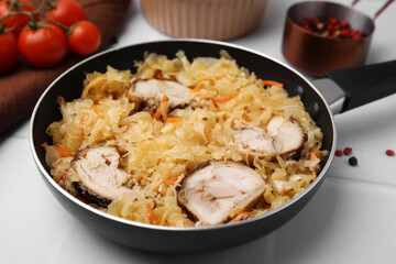 Frying pan with sauerkraut, and chicken on white tiled table