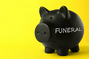 Money for funeral expenses. Black piggy bank on yellow background, space for text