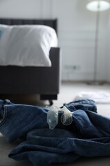 Unrolled condom and jeans on floor in bedroom. Safe sex