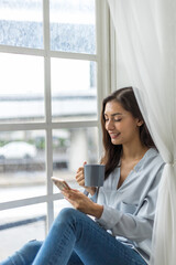 Content Creator Enjoying Coffee and Smartphone by the Window