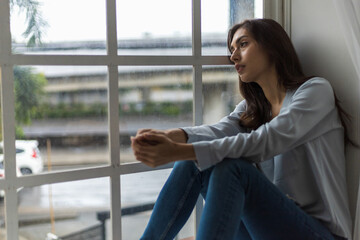 Young Woman Feeling Blue, Gazing Out the Window on a Rainy Day.