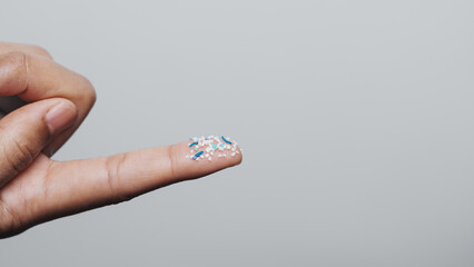 Climate change idea. Close up microplastics lay on female people finger hand. it's very small.