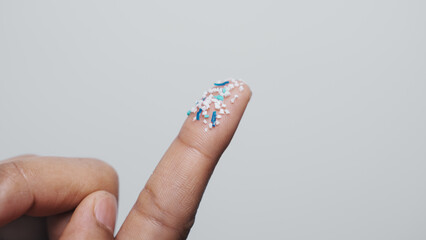 Climate change idea. Close up microplastics lay on female people finger hand. it's very small.