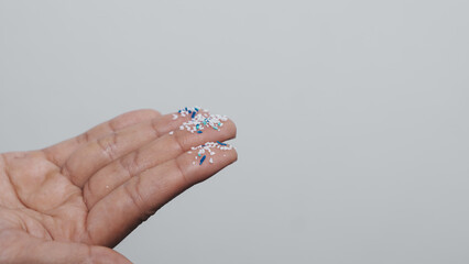 Climate change idea. Close up microplastics lay on female people finger hand. it's very small.