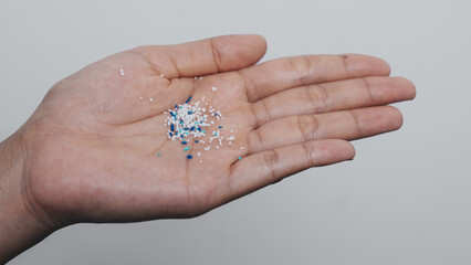 Climate change idea. Close up microplastics lay on female people finger hand. it's very small.