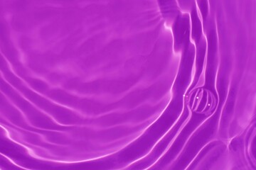 Purple water with ripples on the surface. Defocus blurred transparent blue colored clear calm water surface texture with splashes and bubbles. Water waves with shining pattern texture background.