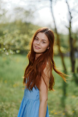 Portrait of a woman outdoors in spring in a blue dress looking at the camera, happiness outside, sunshine walk 