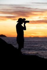 silhouette of a photographer with a beautiful sunrise in the background on Leblon beach in Rio de...
