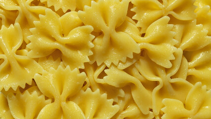 Background yellow pasta in shape of butterflies close-up