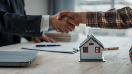 Shaking hands, Real estate agent with client considering buying a new home To pay a bribe to sign to approve the purchase, bribery concept.