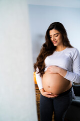 Portrait of Young beautiful pregnant woman holding her belly and smiling