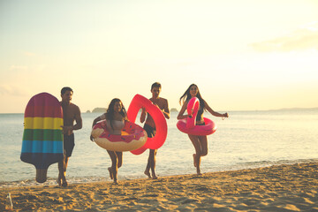 Group of friends having fun swimming and running on the tropical summer beach