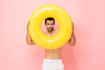 Handsome young man face in the middle of rubber ring summer portrait studio concept in pink color...