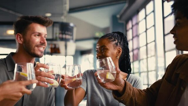Group of multi-cultural friends meeting in restaurant doing cheers with water to celebrate  - shot in slow motion