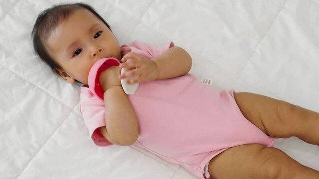 infant baby biting mushroom teether rubber toy on a bed