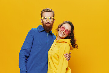Man and woman couple smiling cheerfully and crooked with glasses, on yellow background, symbols signs and hand gestures, family shoot, newlyweds.