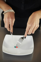 Pills, plate and hands of woman with cutlery for anorexia, eating disorder and weight loss issue....
