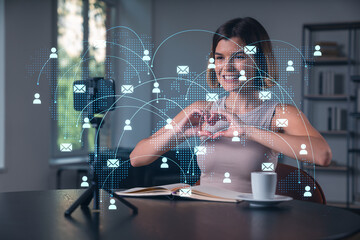 Happy woman is making video blog using smartphone on a tripod explaining with hands at office workplace. Concept of online stream, business education, conference call. Social network hologram