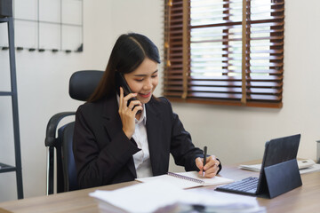 Secretary concept, Female secretary talking on phone with executive and taking notes in notebook