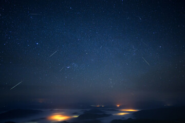 geminid meteor shower over misty mountains landscape
